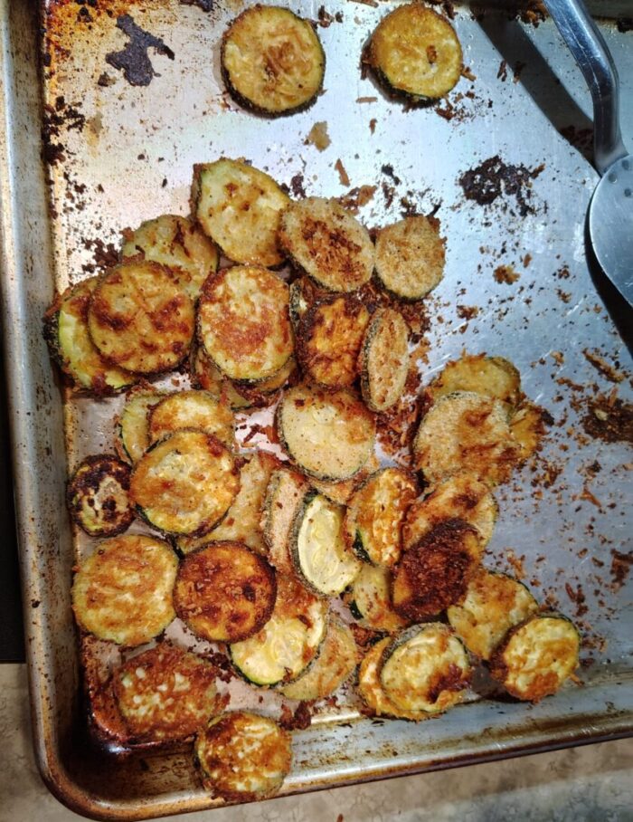a of zucchini crisps: thin zucchini rounds, battered in breadcrumbs and parmesan and roasted until golden