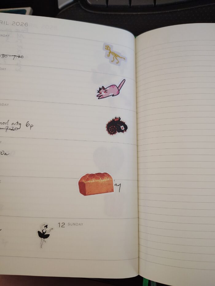 stickers in my planner featuring a t-rex skeleton, a cat, a dragon drinking a juice box, a loaf of bread, and a ballerina