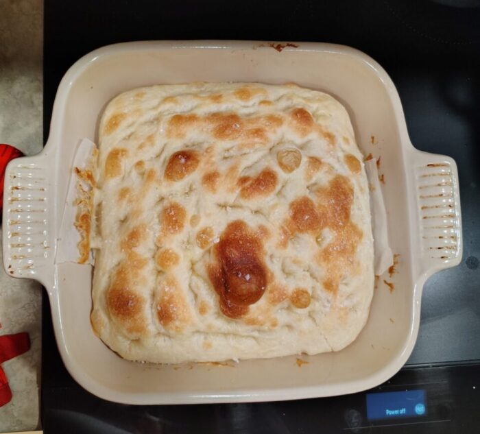 a square pan of foccacia bread with pleasing bubbles browned on top