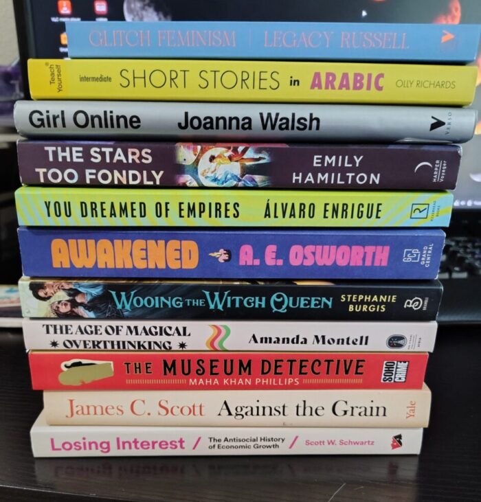 A pile of 11 books, including a diverse mix of fiction and non-fiction