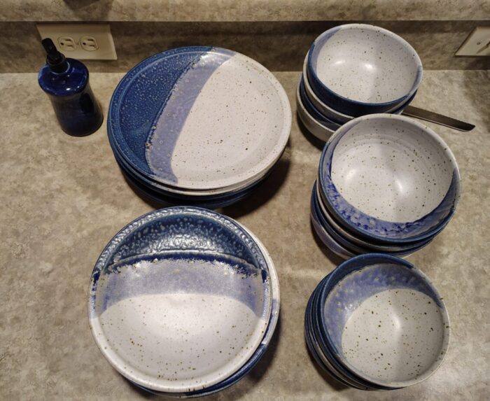 Plates and bowls, each of two sizes, on my kitchen counter. They are ceramic and white with a light blue to dark blue gradient, and brown speckles throughout