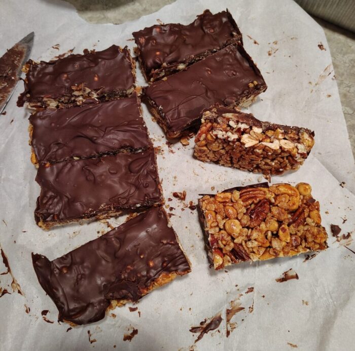 a batch of granola bars consisting of nuts and a layer of chocolate. the bars are holding their shape, unlike last time.