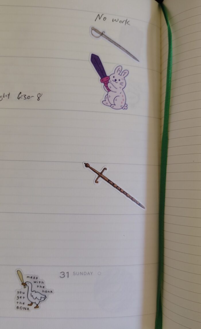 stickers in my planner featuring two different swords, a cartoon bunny with a sword, and a goose wielding a baseball bat