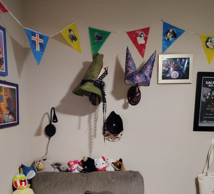 two hat stands in my office, one displaying a green witch hat and another with the double henin from my jester outfit