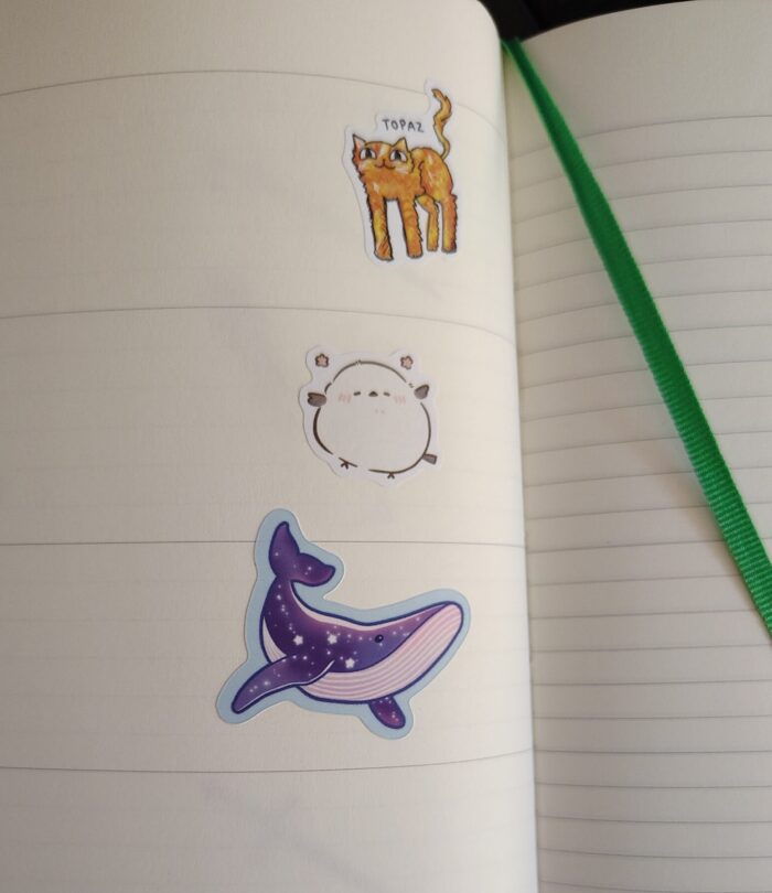 stickers of an orange cat with long legs, a puffball of a bird, and a celestial whale