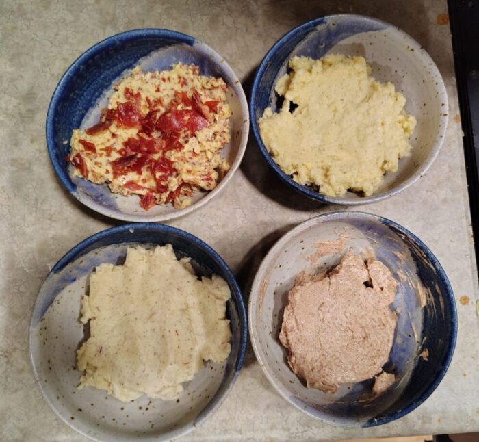 four small bowls of compound butters: cinnamon sugar, saffron and honey, cheddar cheese, and prosciutto