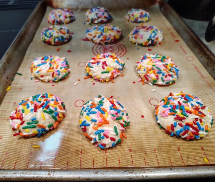 a sheet pan of small sugar cookies completely coated in rainbow sprinkles