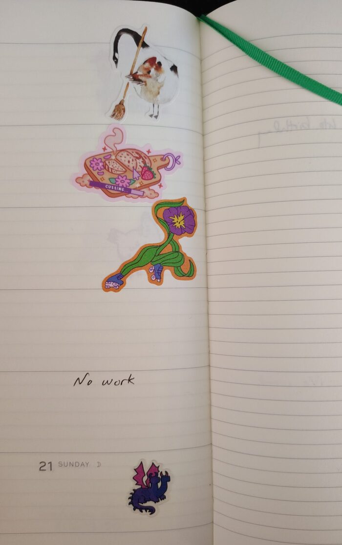 stickers in my planner featuring a goose sweeping, a loaf of bread, a flower on roller skates, and a bisexual dragon