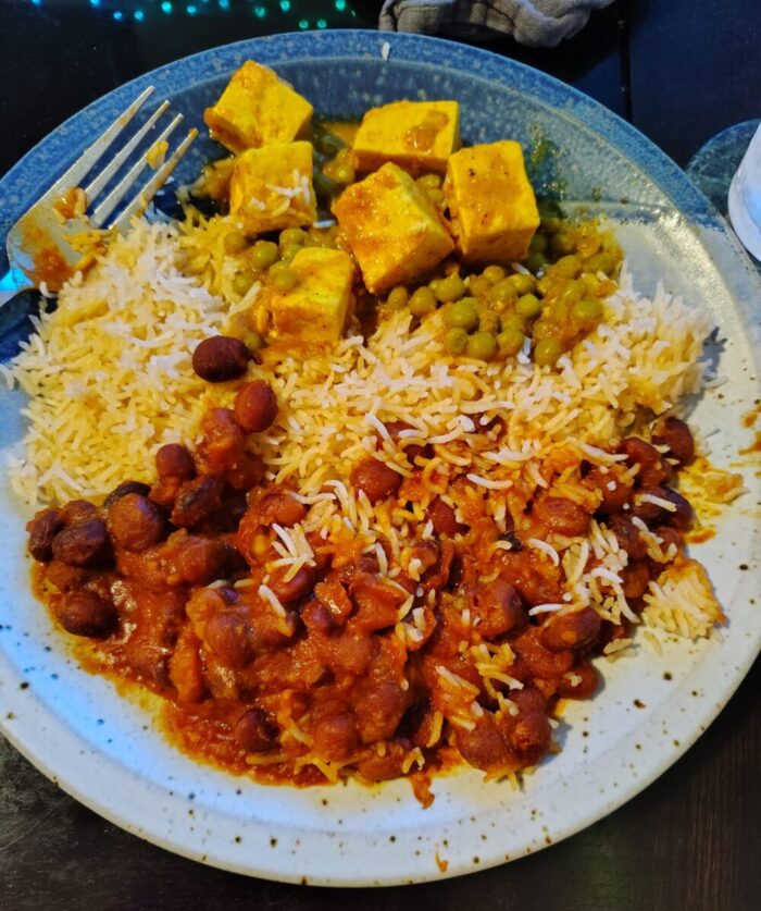 unattractive photo of peas and cheese, rice, and bean curry arranged on a plate but kind of mixed up in bad lighting
