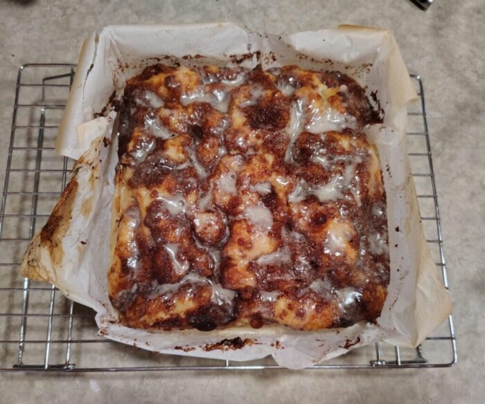 a batch of cinnamon roll focaccia, topped with cinnamon sugar and then a glaze