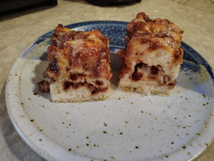 two pieces of cinnamon roll focaccia, showing the middle is full of cinnamon bits