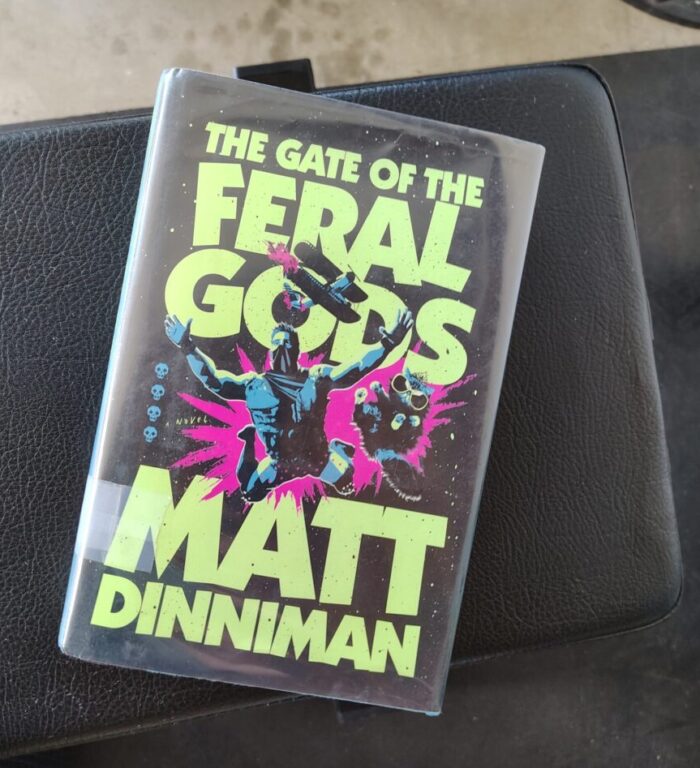 hardcover book: The Gate of the Feral Gods. Cover features Carl and Princess Donut leaping away from an exploding plane