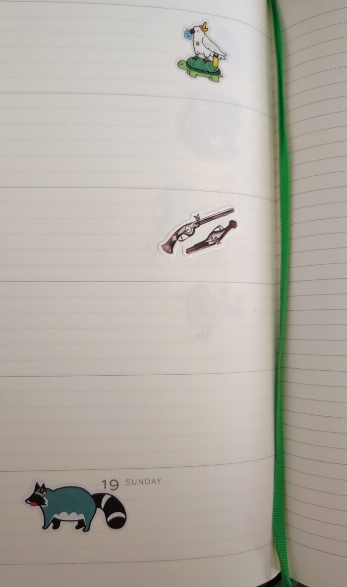 stickers in my planner featuring a bird riding a turtle, pistols, and a fat raccoon
