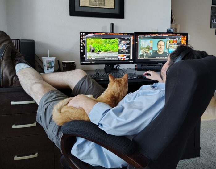 Fritz the cat lounging on top of Kirk. They are both looking at youtube videos on the computer