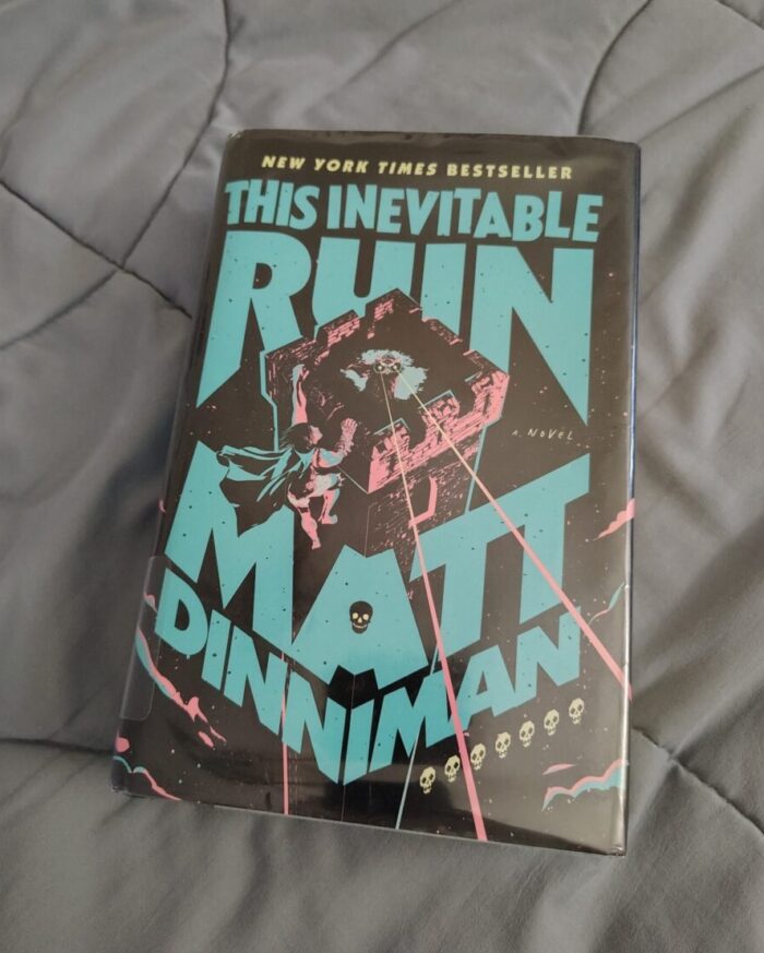 book: This Inevitable Ruin. Cover features a cat atop a tower shooting lasers from her eyes