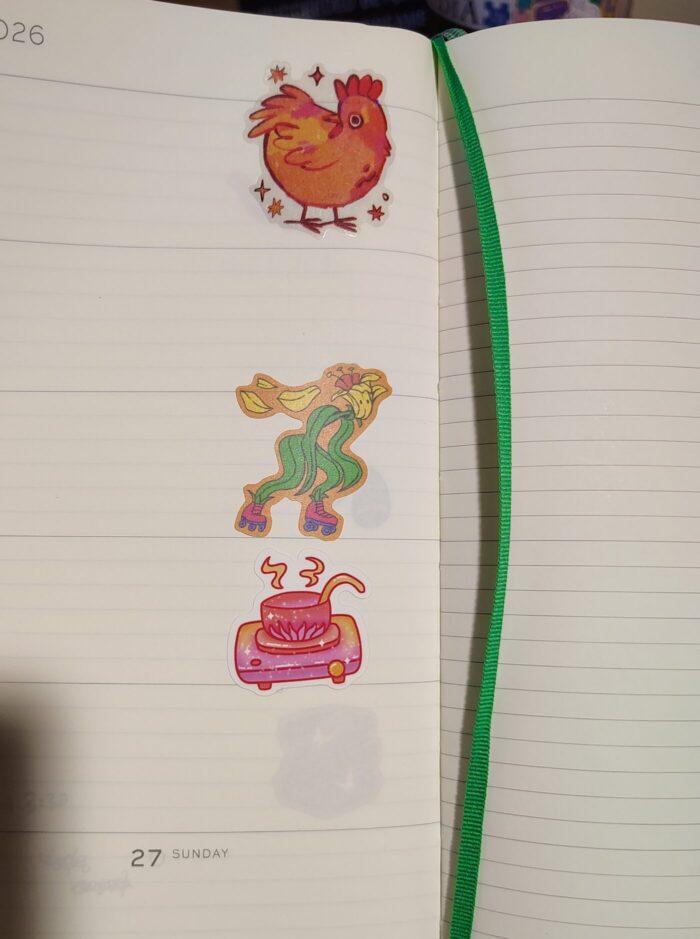 stickers in my planner featuring a sparkly chicken, a flower on roller skates, and a pot of soup