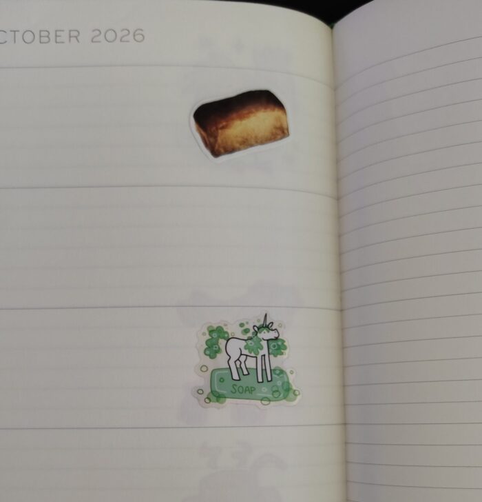 stickers in my planner featuring a photo-realistic loaf of bread and a soapy unicorn