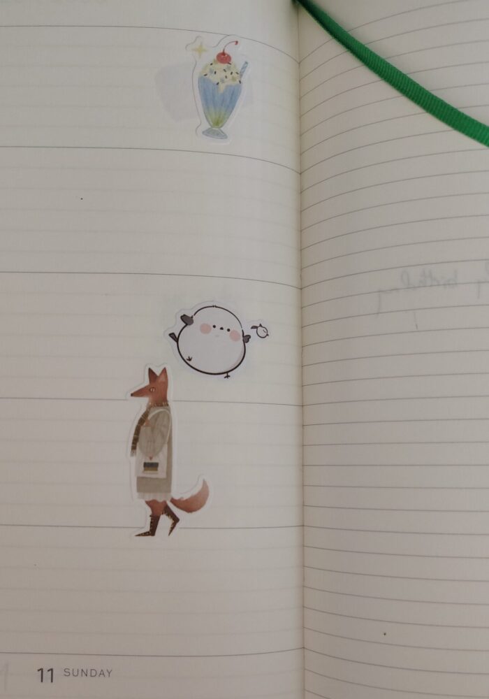 stickers in my planner featuring a milkshake, a very round bird, and a fox walking around with a tote bag