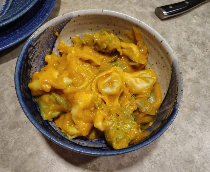 a bowl of tortellini smothered in sauce made from pureed squash