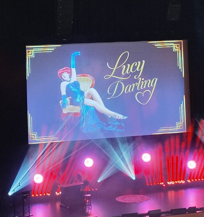 screen above the stage at the Lucy Darling show featuring an image of the diva herself